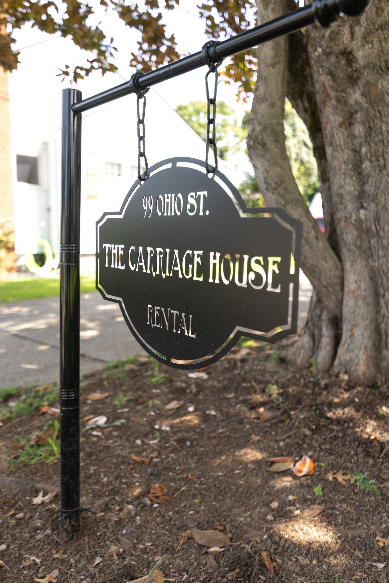 A hanging sign for '99 Ohio St. The Carriage House Rental.'