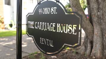 A hanging sign for '99 Ohio St. The Carriage House Rental.'