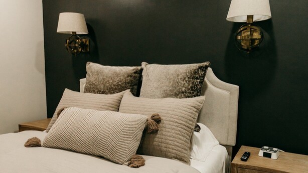 A bedroom with a bed, two bedside lamps, a nightstand, and a wooden floor. - NEW Luxury Carriage House Downtown Somerset (Somerset)