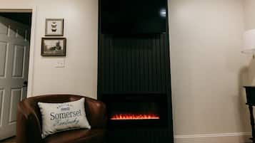 A living room with a leather armchair, a fireplace, a rug, and a door.