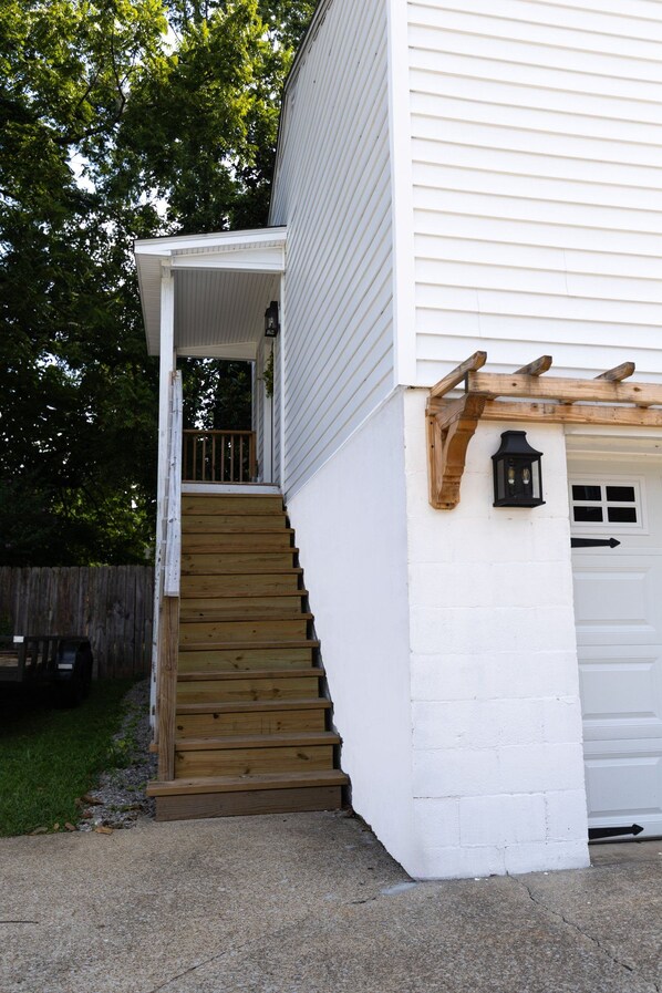 A white house with a wooden staircase leading to a covered porch.