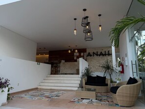 Eine Hotelhalle mit Treppe, Sitzgelegenheiten und einer Rezeption.