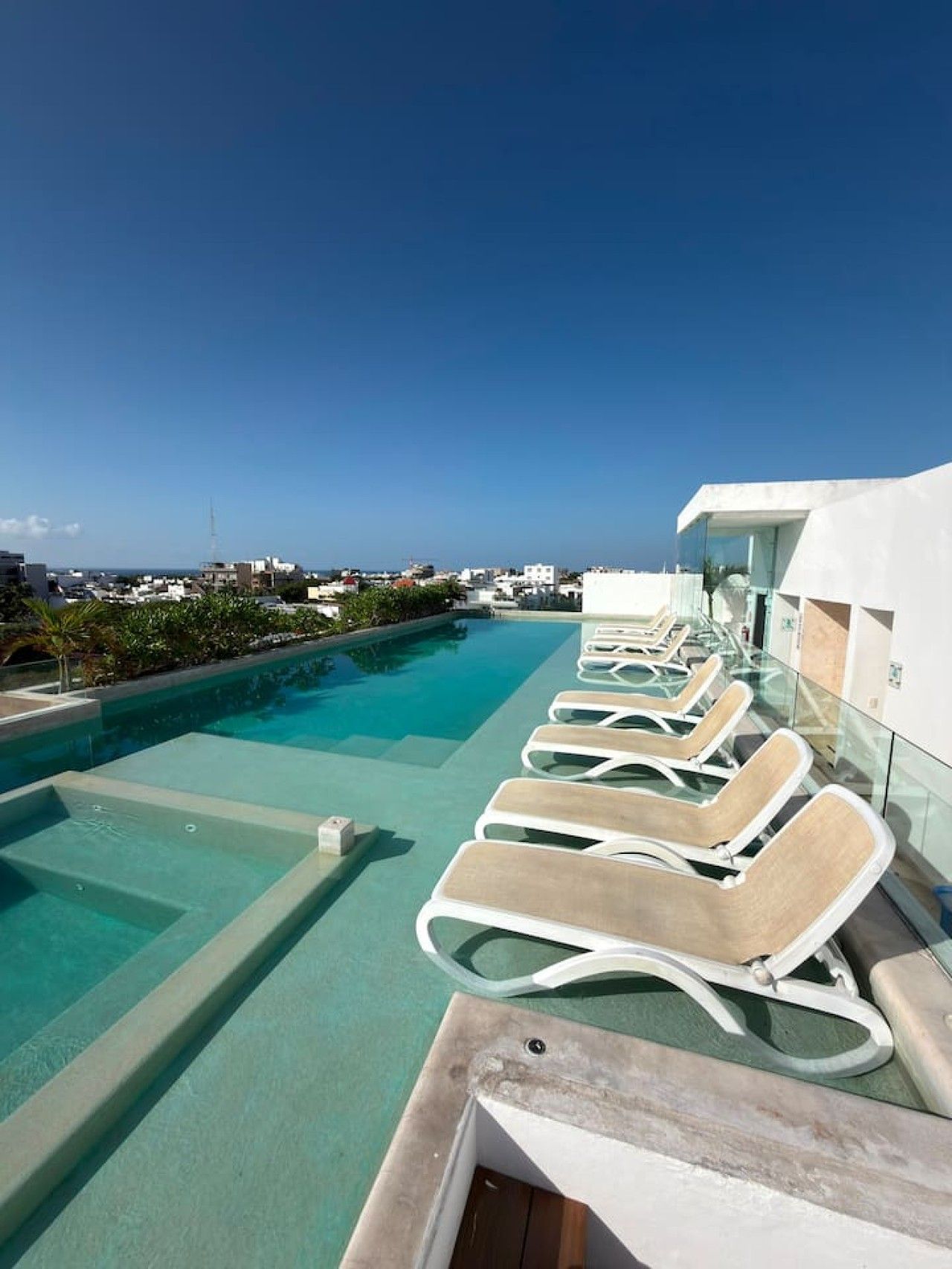 A rooftop pool with lounge chairs and a clear view of the cityscape.