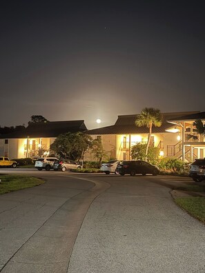 A residential area at night with a clear moon in the sky, parked cars, and a building with a visible entrance. - Cozy, Quiet 2 bed/2bath condo in Saddlebrook (Zephyrhills)