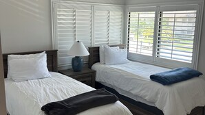 A room with two beds, a nightstand with a lamp, and a window with blinds. - Cozy 2-bed/2 bath condo in Saddlebrook Resort (Zephyrhills)