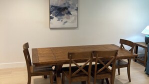A dining area with a wooden table and chairs, a painting on the wall, and a ceiling light. - Cozy 2-bed/2 bath condo in Saddlebrook Resort (Zephyrhills)