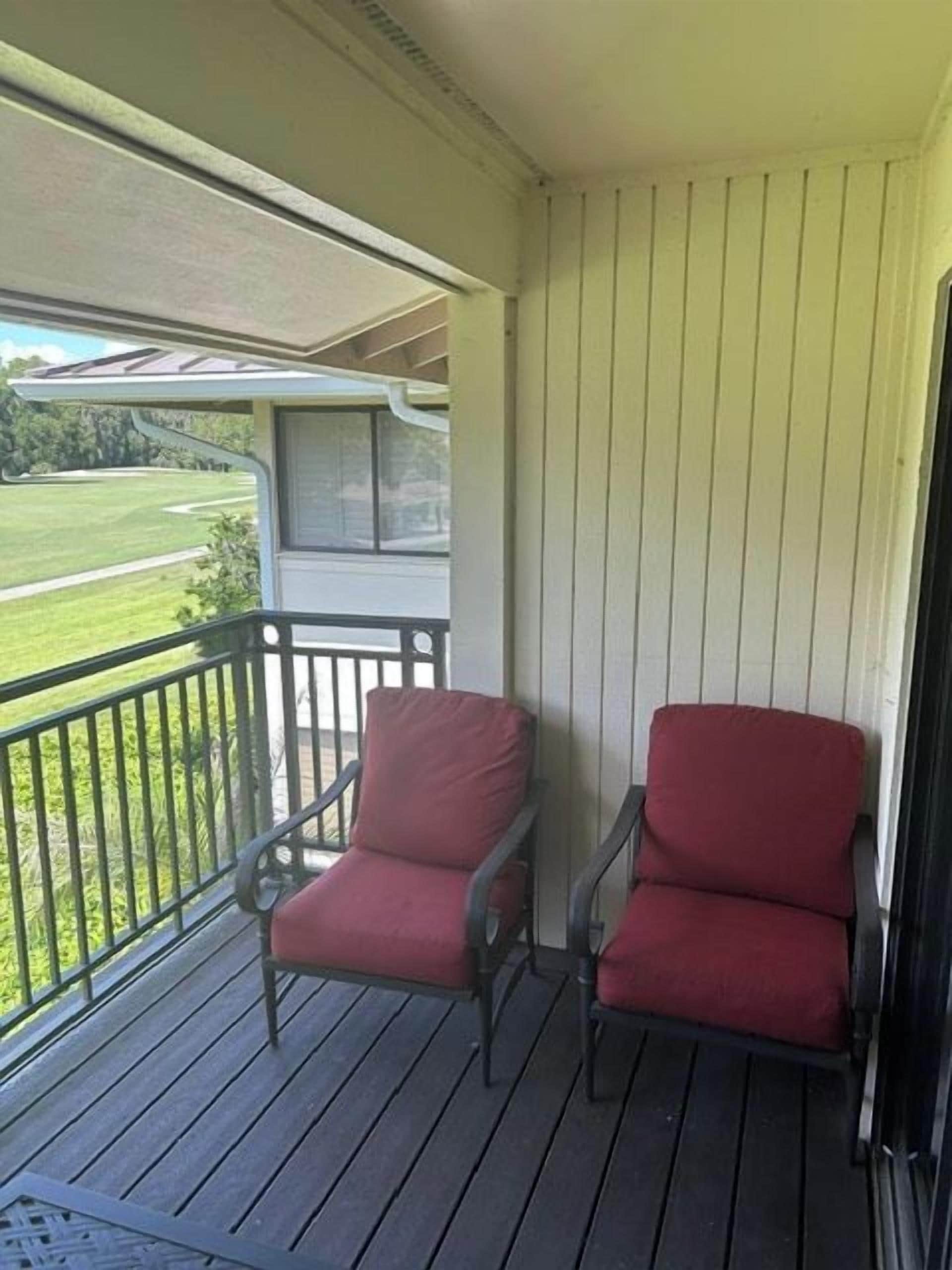 A balcony with two chairs and a view of a green landscape.