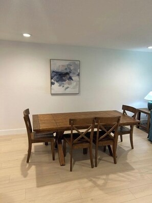 A dining area with a wooden table and chairs, a framed abstract painting on the wall, and a lamp on a side table. - Cozy, Quiet 2 bed/2bath condo in Saddlebrook (Zephyrhills)