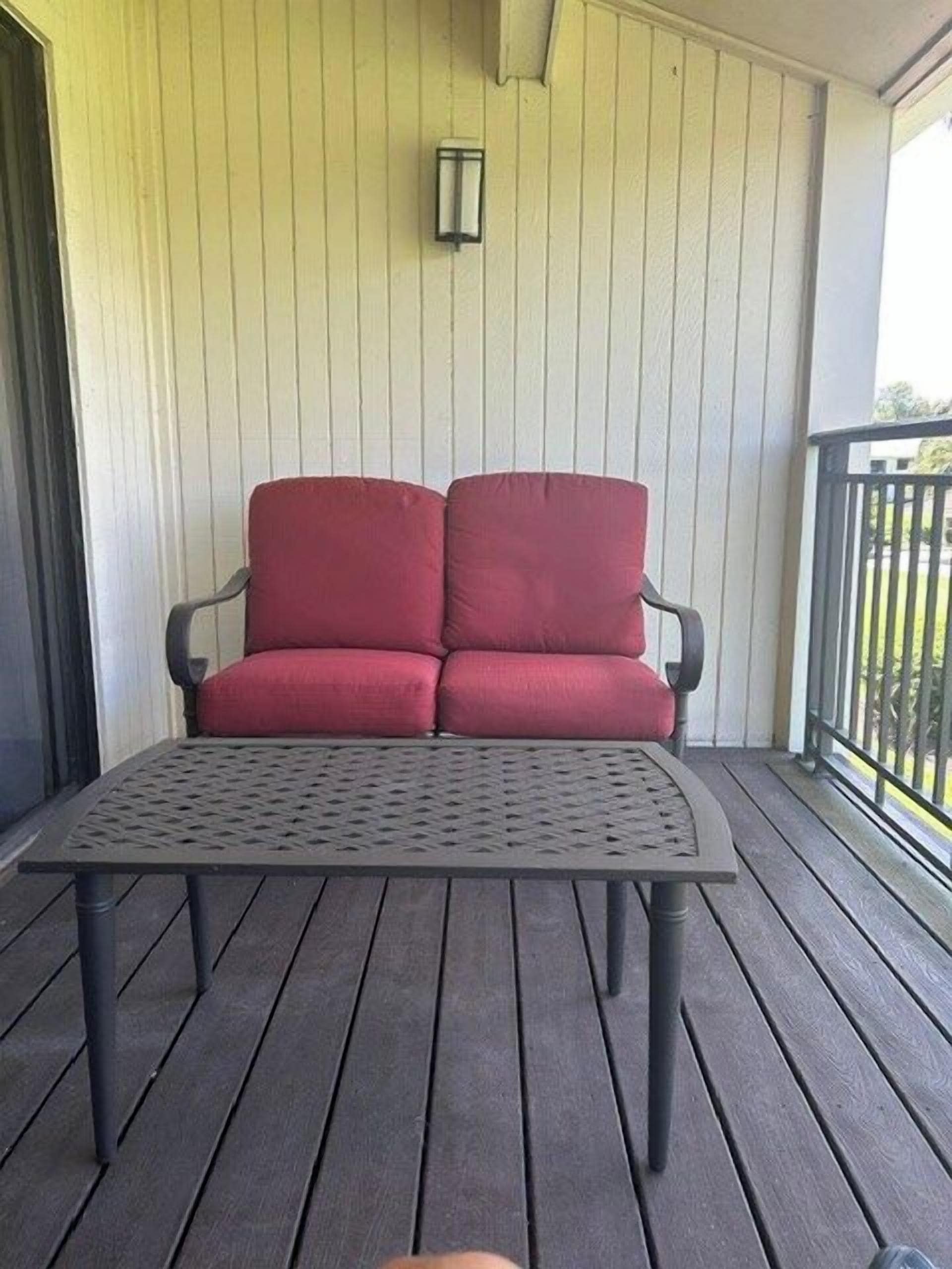 A balcony with a red sofa and a metal table.