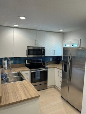 A modern kitchen with stainless steel appliances, a double sink, and light-colored cabinetry. - Cozy, Quiet 2 bed/2bath condo in Saddlebrook (Zephyrhills)