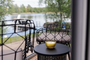 Un balcón con una mesa, sillas, una vela y vistas a un lago.