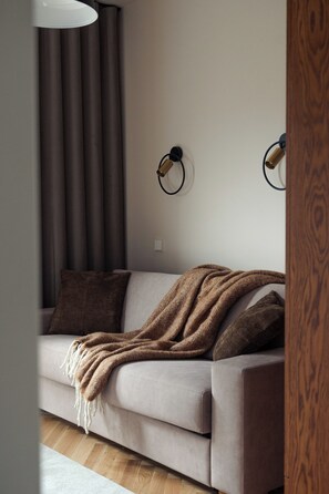 A modern living room with a sofa, a throw blanket, and a wall-mounted lamp.
