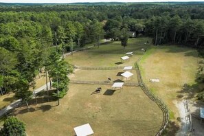 A fenced property with multiple white structures, possibly shelters or buildings, surrounded by a wooded area.