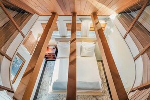 A room with a wooden ceiling, a bed with pillows, and a small table.