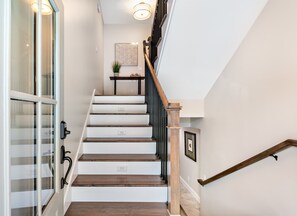 A staircase with wooden steps and black railings, leading to a landing with a small table and a plant.