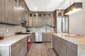 Una cucina moderna con mobili in legno, elettrodomestici in acciaio inossidabile e un piano di lavoro in marmo.