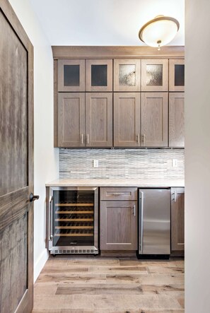 Una cocina con armarios de madera, un enfriador de vino y un refrigerador de acero inoxidable.