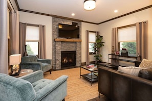 A living room with a fireplace, two sofas, a coffee table, and a TV mounted on the wall.