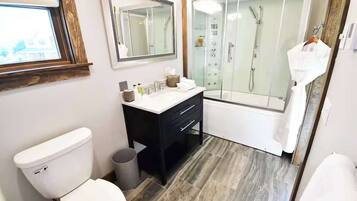 Un baño moderno con inodoro, lavamanos, espejo y ducha con mampara de vidrio.