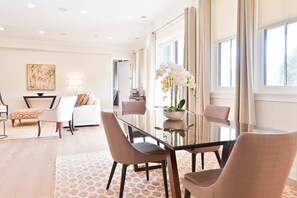 A modern dining area with a glass table, cushioned chairs, and a vase of flowers.
