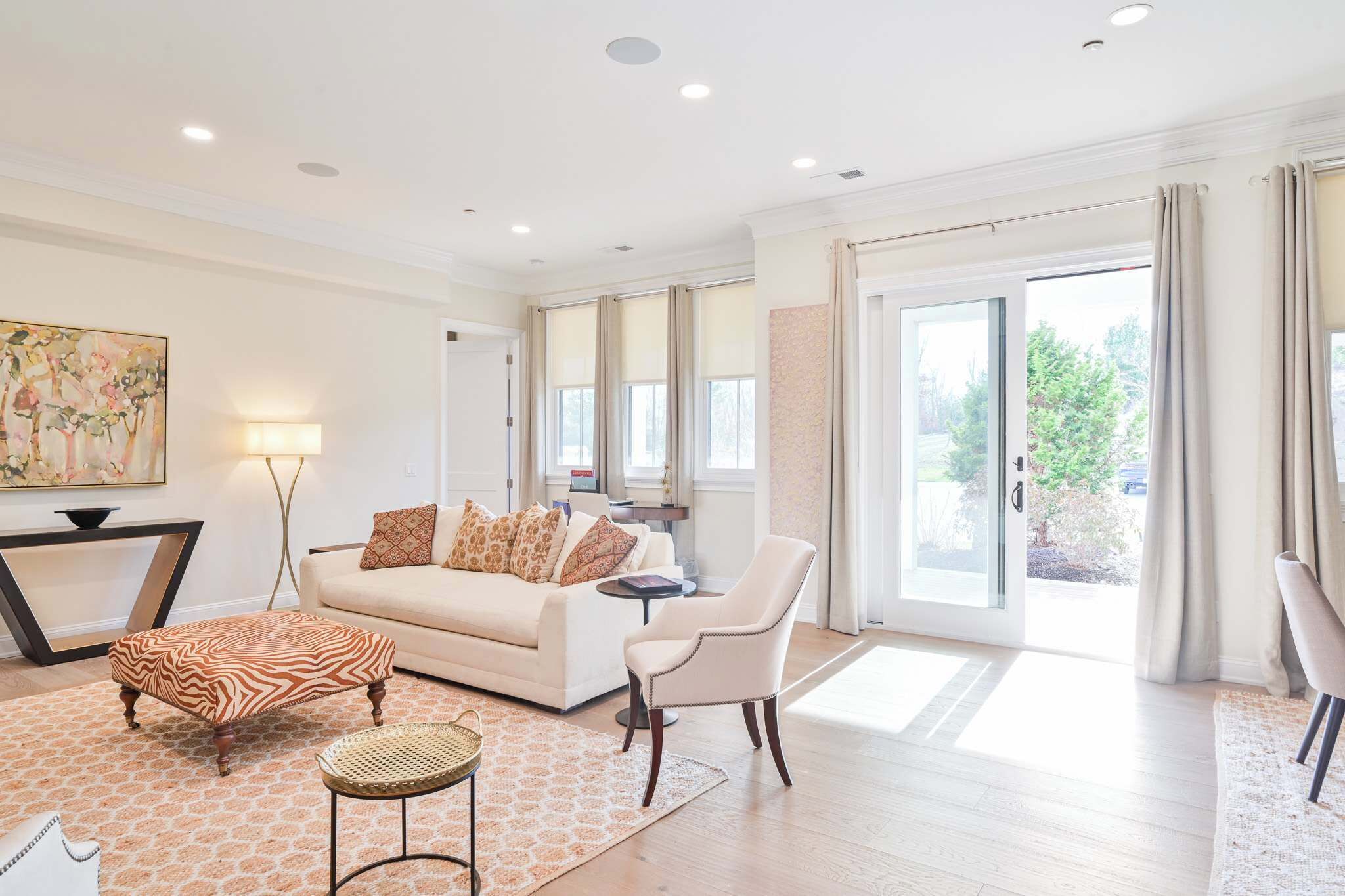 A spacious living room with a sofa, armchair, ottoman, and a dining table.