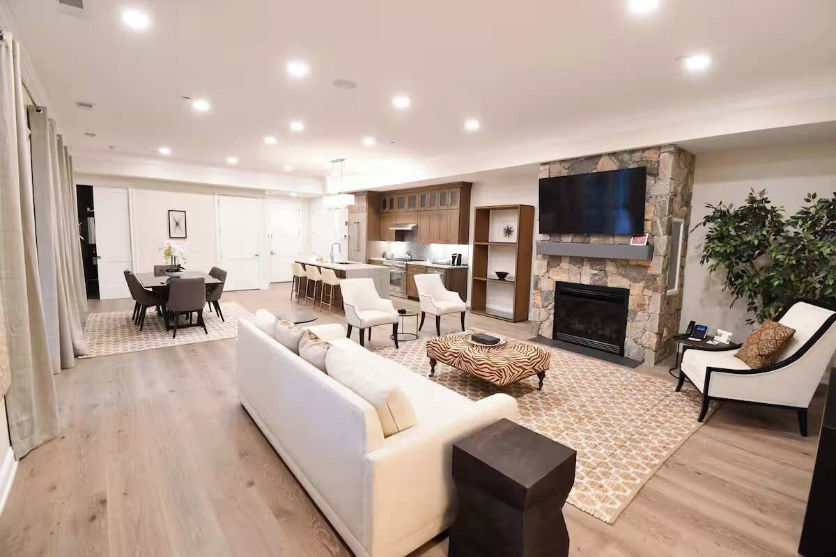 Ein modernes Wohnzimmer mit einer Couch, Sesseln, einem Kamin und einem Fernseher.