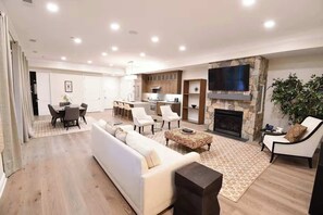 A modern living room with a sofa, chairs, a fireplace, and a television. - Hilltop | Village Two Bedroom Suite (Richmond)