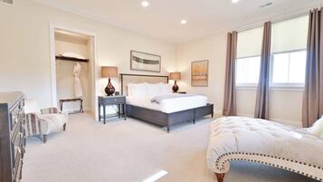 A bedroom with a bed, bedside tables, a dresser, a walk-in closet, and a window with curtains.