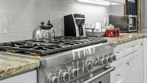 Une cuisine moderne dotée d’appareils électroménagers en acier inoxydable, de meubles blancs et d’un plan de travail en granit.