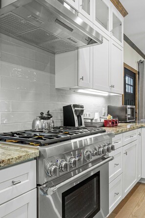 A modern kitchen with stainless steel appliances, white cabinetry, and a granite countertop.
