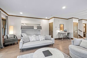 A modern living room with a sofa, a round coffee table, a desk, and a wardrobe.