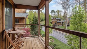 Une terrasse en bois, agrémentée de mobilier d’extérieur, qui offre une vue sur un quartier résidentiel avec ses maisons et ses arbres.