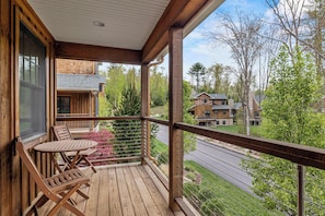 A wooden deck with outdoor furniture, overlooking a residential area with houses and trees.