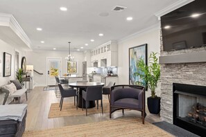 Una sala de estar moderna con chimenea, comedor y cocina.