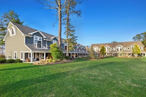 A residential area with multiple houses, a well-maintained lawn, and a clear sky.