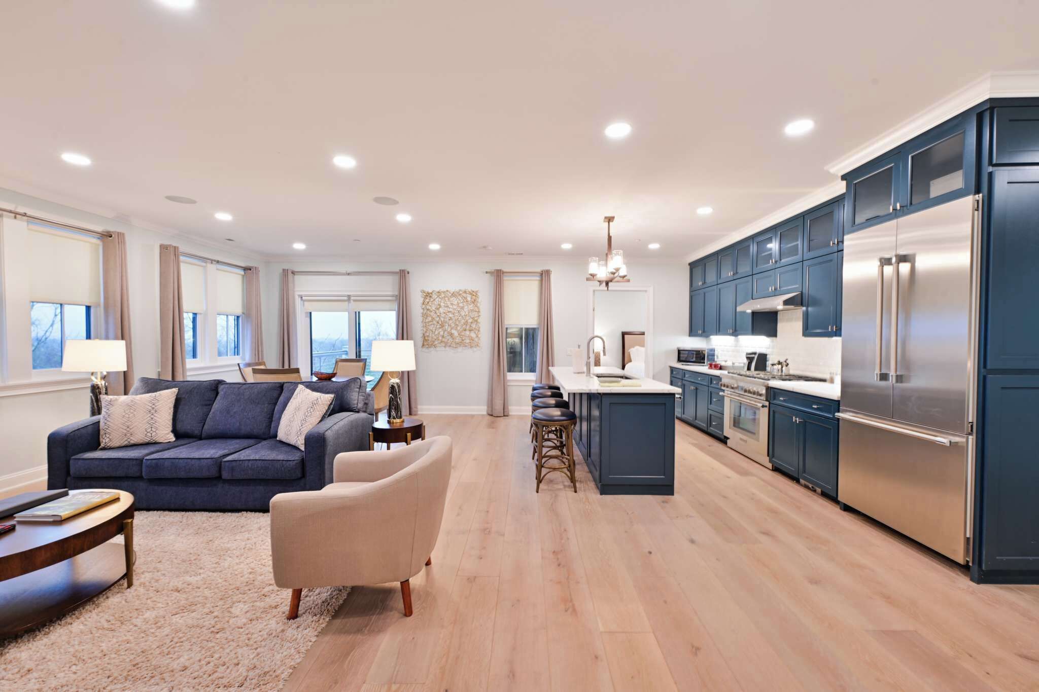 A modern kitchen with dark blue cabinets, stainless steel appliances, and a central island.