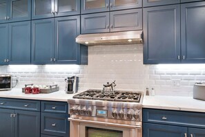 Une cuisine avec des meubles de couleur bleu foncé, une cuisinière en acier inoxydable et un four à micro-ondes.