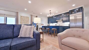 A modern kitchen with dark blue cabinets, a stainless steel refrigerator, and a central island with stools.
