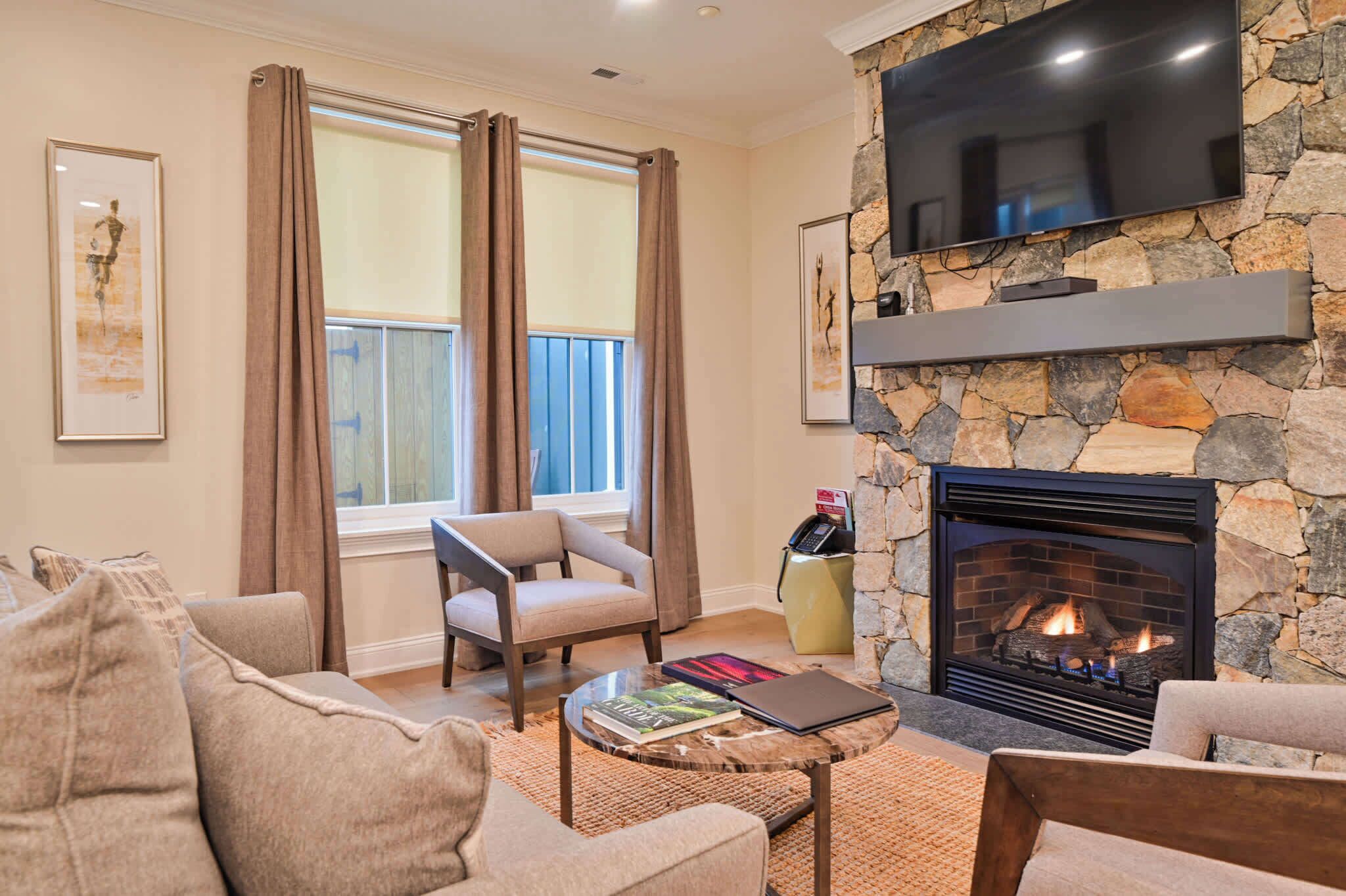 A living room with a stone fireplace, a flat-screen TV mounted on the wall, a sofa, and a coffee table.