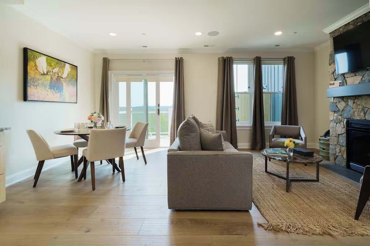 A spacious living room with a sofa, dining table, chairs, and a fireplace.