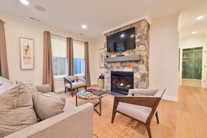 A living room with a stone fireplace, a flat-screen TV, and a sofa.