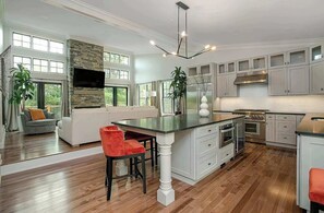 A modern kitchen with a central island, built-in appliances, and a stone accent wall.