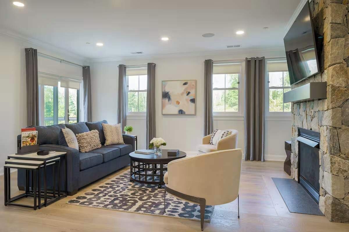 A living room with a sofa, armchair, coffee table, and fireplace.