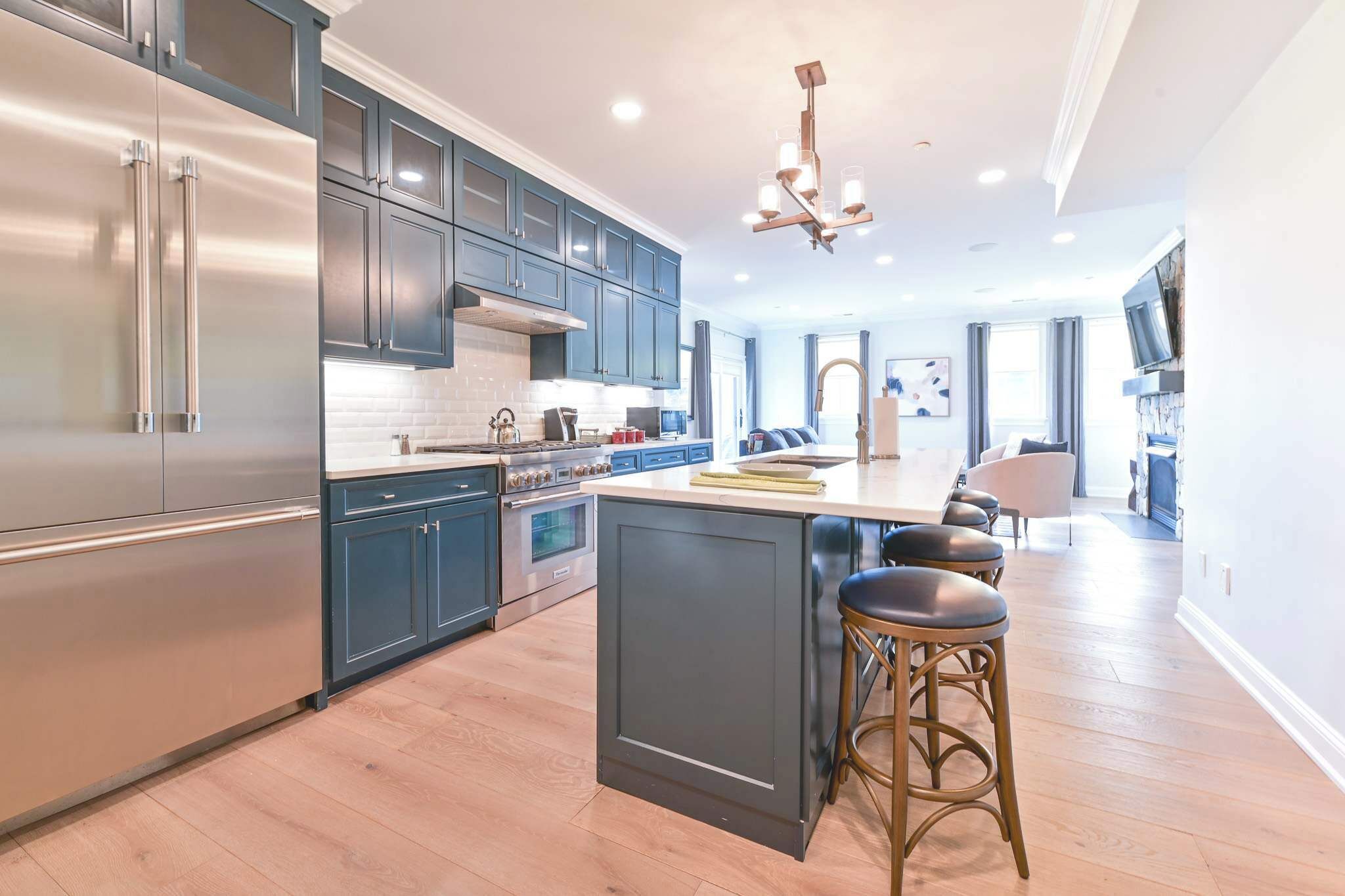 A modern kitchen with stainless steel appliances, dark blue cabinets, and a central island with bar stools.