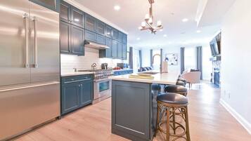 A modern kitchen with stainless steel appliances, dark blue cabinets, and a central island with bar stools.