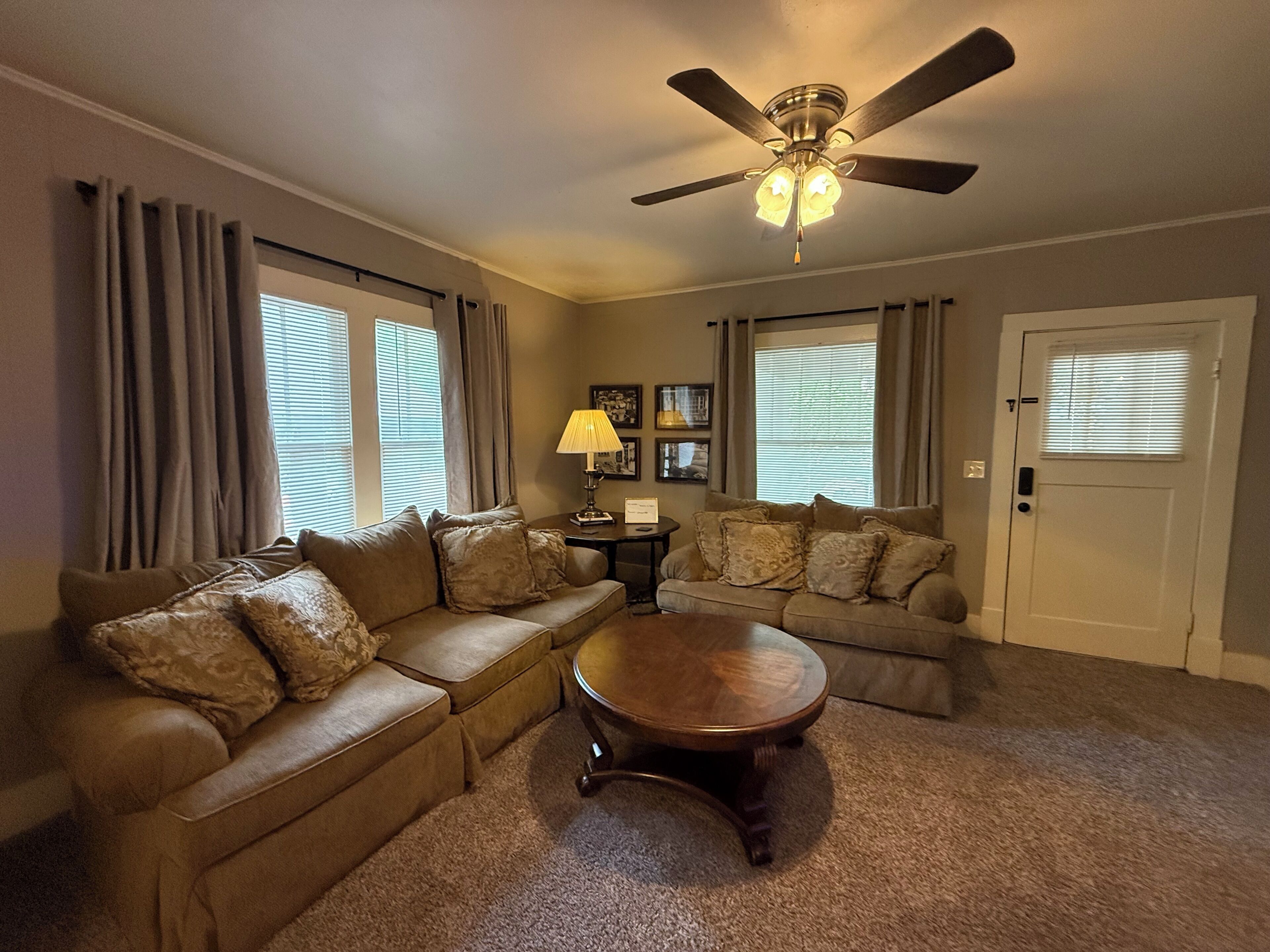 A living room with a ceiling fan, two couches, a coffee table, and a door.