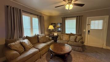 A living room with a ceiling fan, two couches, a coffee table, and a door.