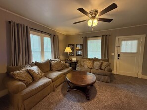 A living room with a ceiling fan, two couches, a coffee table, and a door.