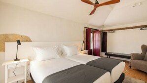 A bedroom with two beds, a ceiling fan, a nightstand, a chair, and a door leading to another room. - Peaceful Farmhouse Stay in Parada de Tibães Portugal Surrounded by Nature (Braga)