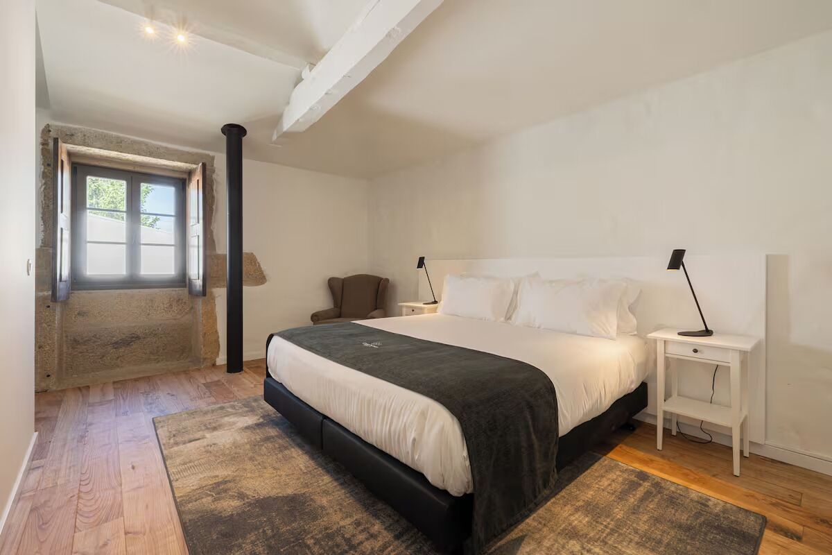 Une chambre à coucher avec un lit, des tables de chevet, une commode, une fenêtre et une porte.